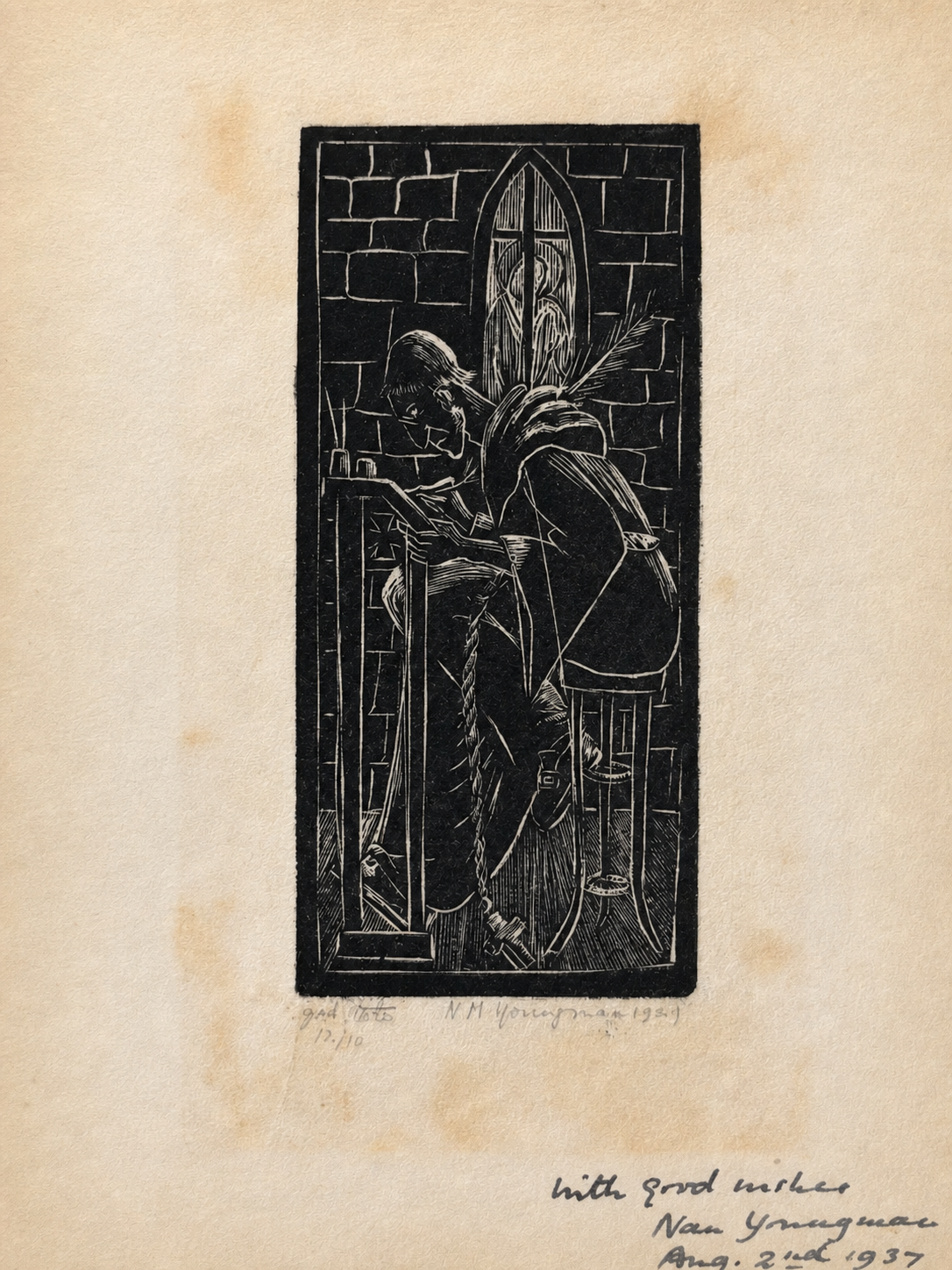 Album page holding a small black relief print of a seated figure beside a tall pointed window, with a handwritten dedication below.