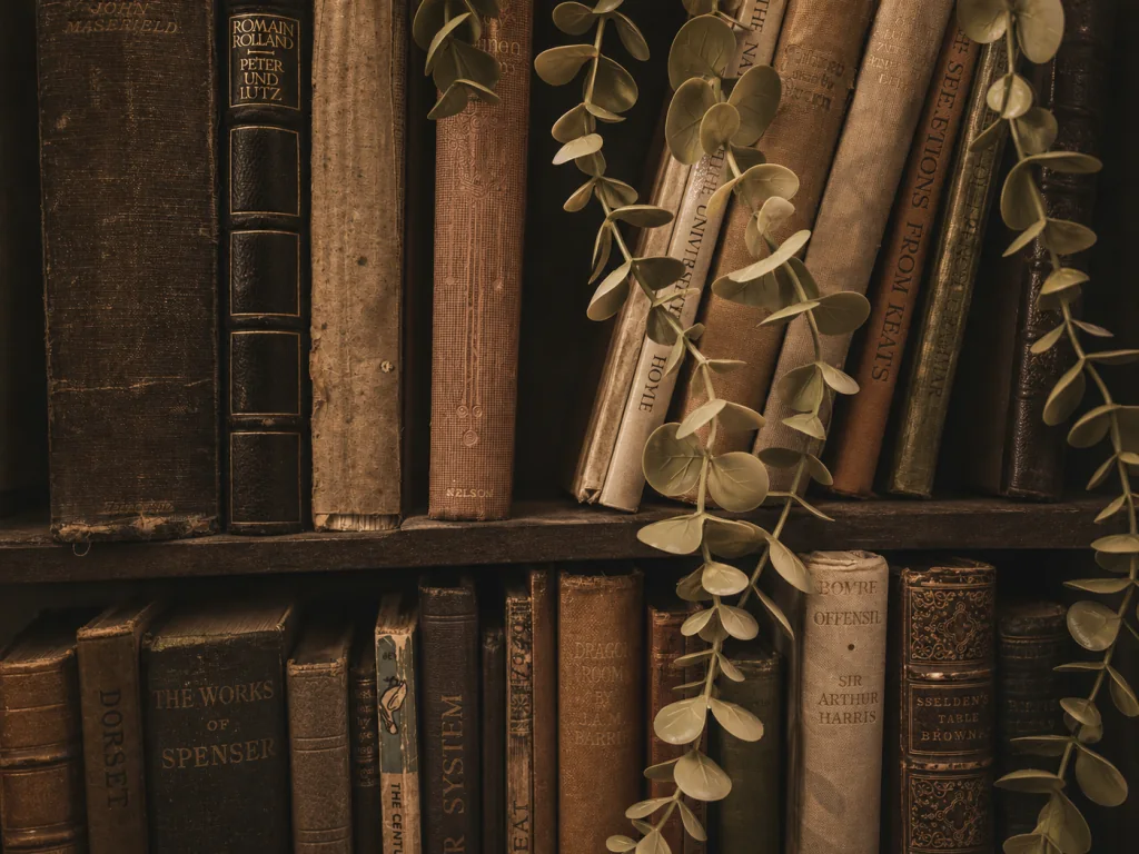 Antique books on a dark bookcase, threaded with a trailing vine