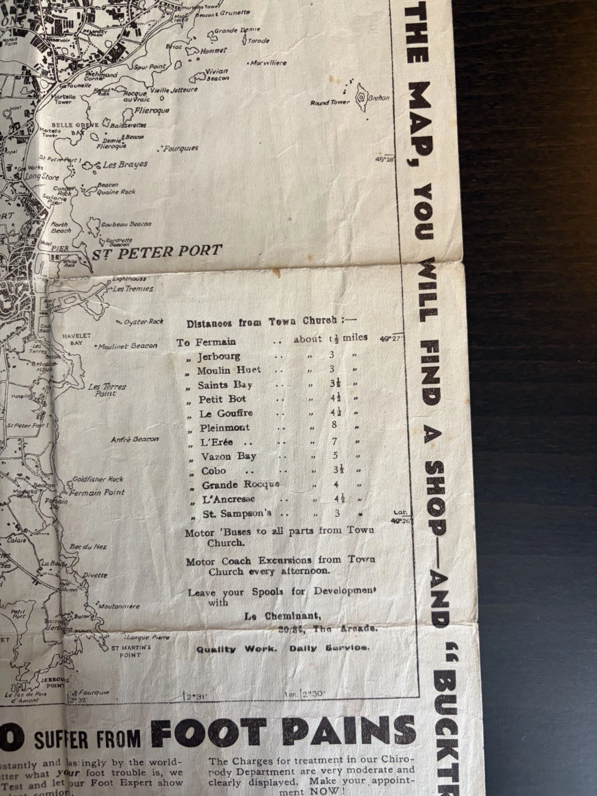 Close view of eastern Guernsey and St Peter Port with distances, motor-bus and coach-excursion notes, film-development advertising and fold wear.
