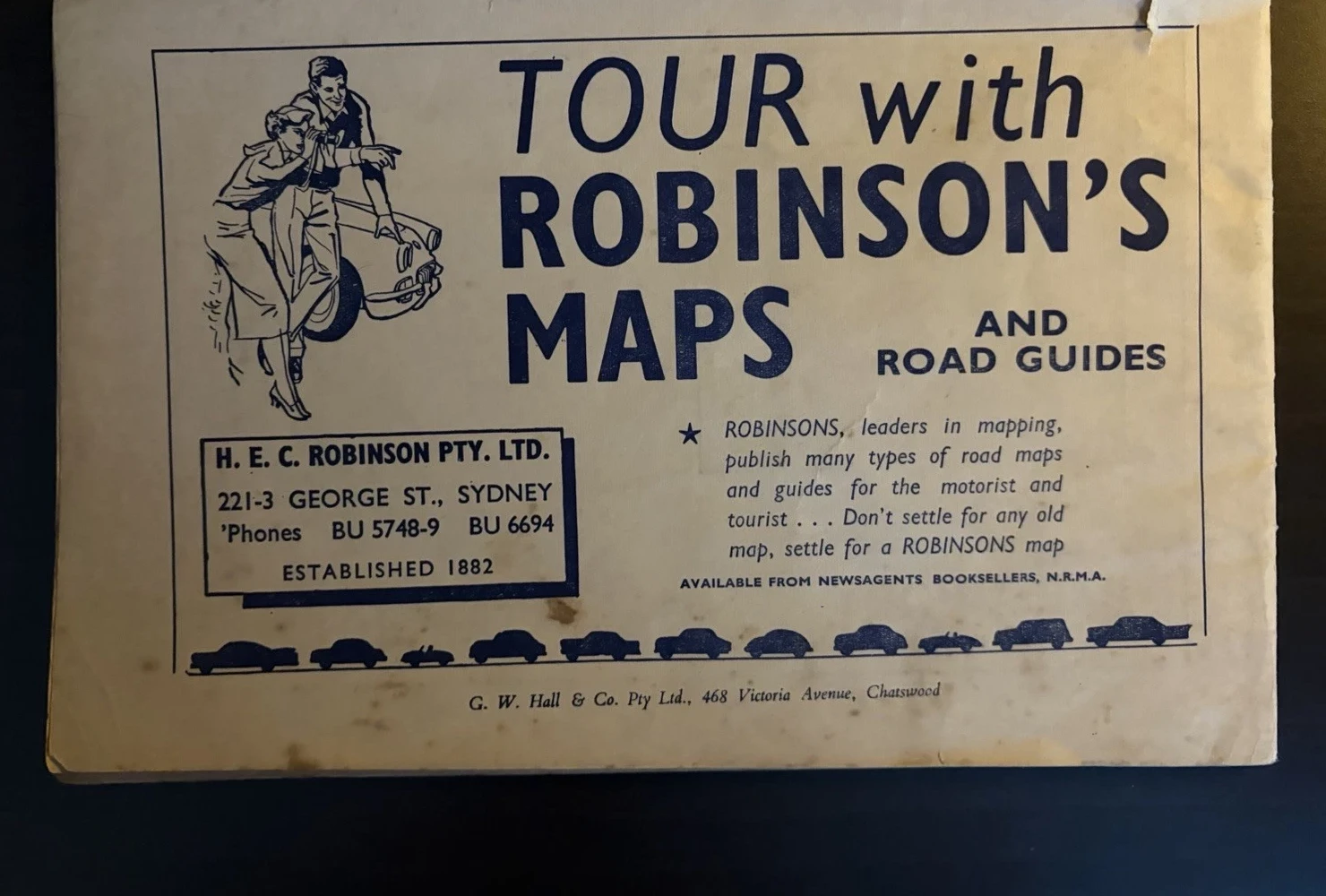 Dark-blue advertisement for H E C Robinson maps and road guides, illustrated with two motorists, a car and a row of vehicle silhouettes.